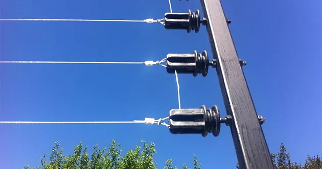 Aisladores de cerco eléctrico con los hilos tensados