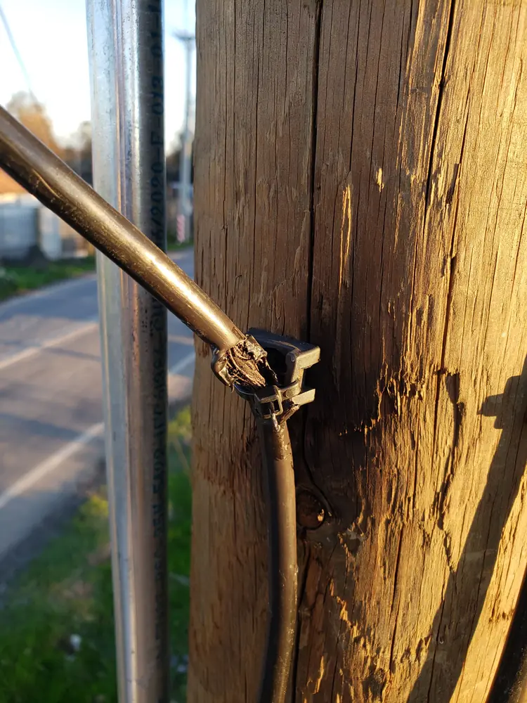 Acometida afianzada a un poste de madera con su soporte