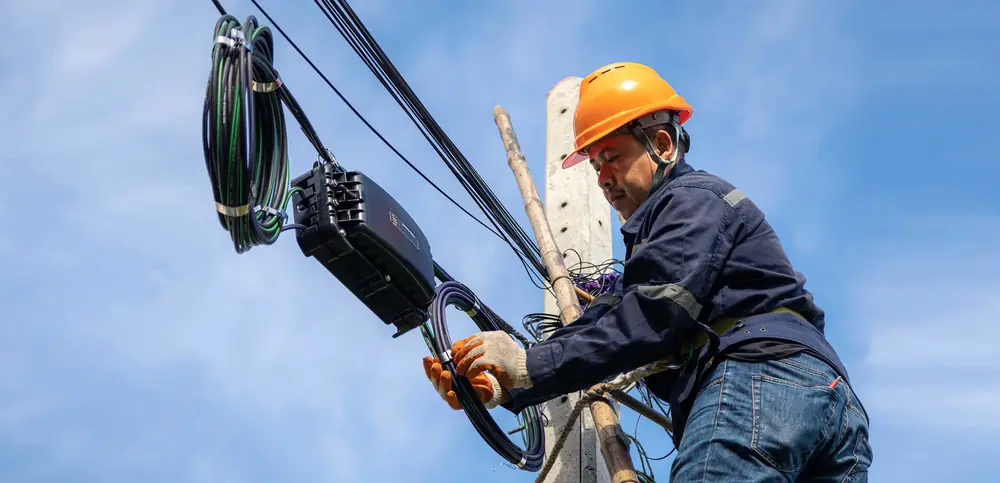 Técnico con casco trabajando en una conexión aérea