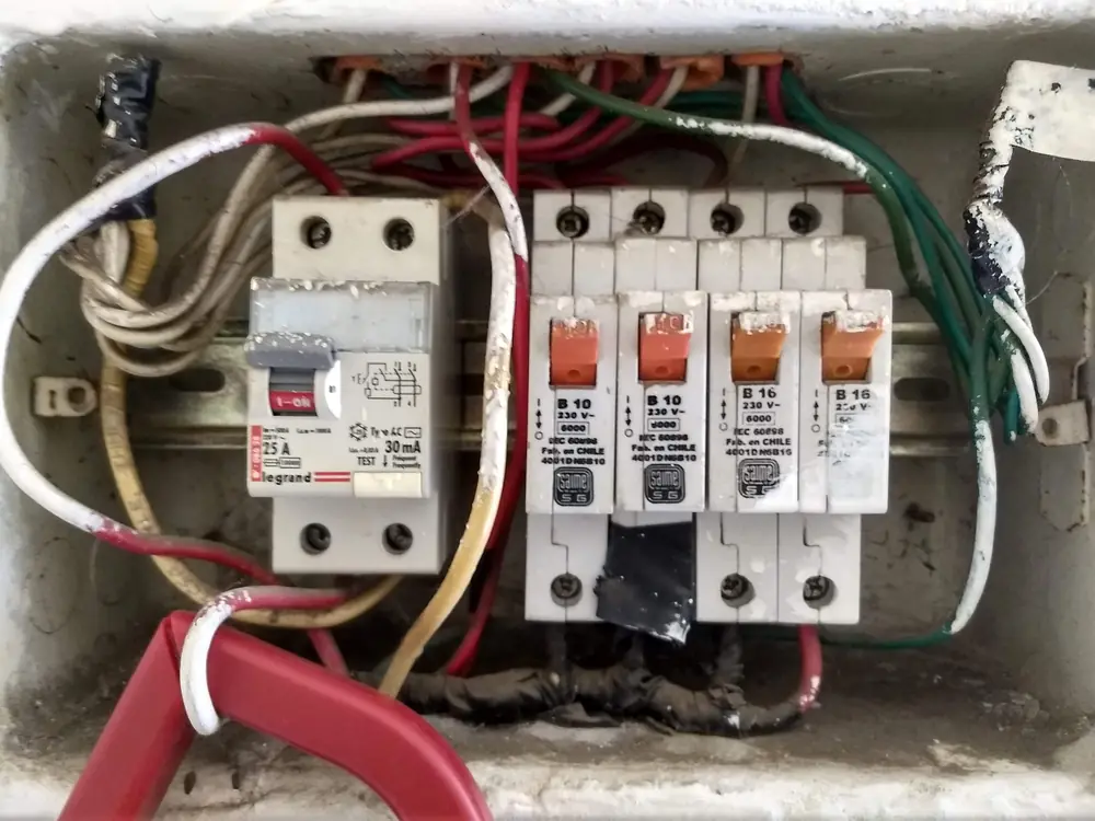 Tablero antiguo con uniones hechas con cinta aisladora y cables sueltos