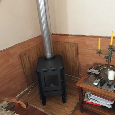 Estufa a leña en una esquina con planchas de protección en los muros y en el piso