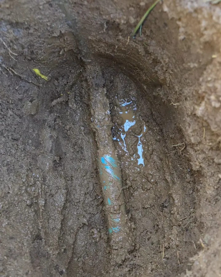 Cañería enterrada a la vista en una excavación de tierra en el patio