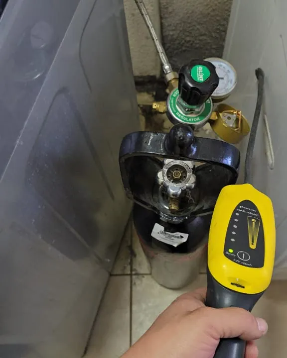 Detector de gas trazador junto al cilindro y la lavadora