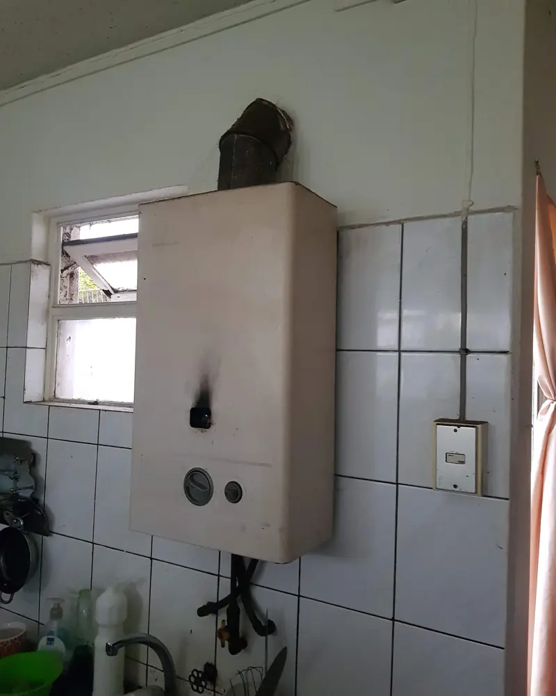 Calefont en una cocina con una mancha negra de hollín en la carcasa