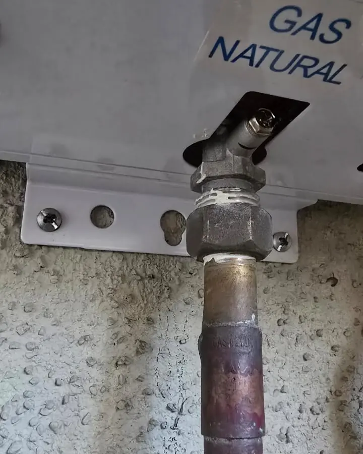 Conexión de cañería de cobre a la entrada de gas de un calefont, con la etiqueta gas natural