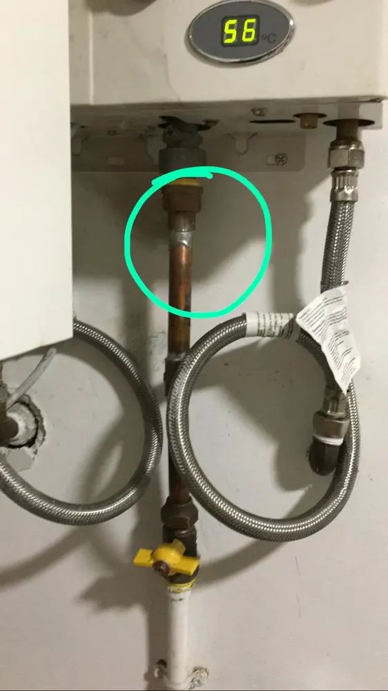 Conexiones de agua bajo un calefont, con una unión de cobre marcada con un círculo