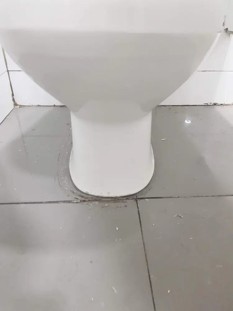 Base de un WC instalado y sellado sobre el piso de cerámica