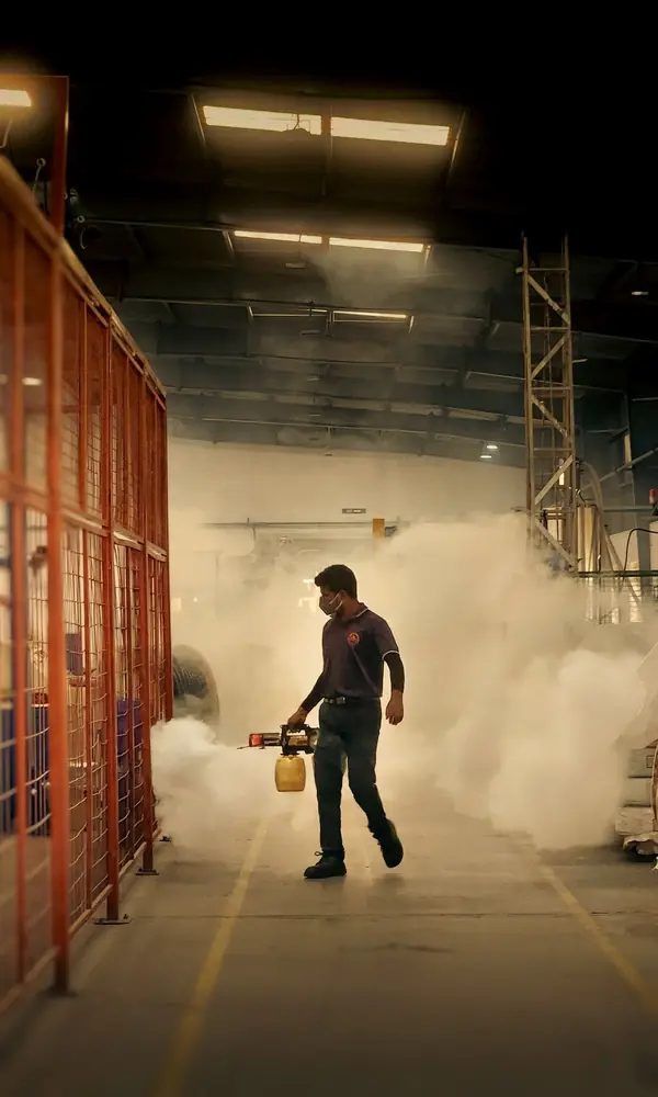 Técnico nebulizando el interior de un galpón industrial