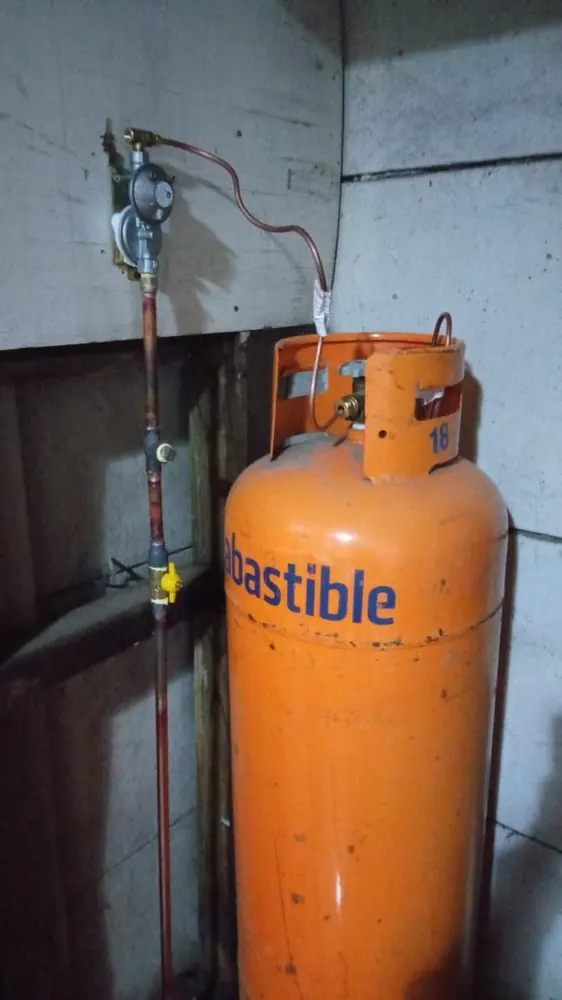 Cilindro de gas de 45 kg con su regulador y una cañería de cobre