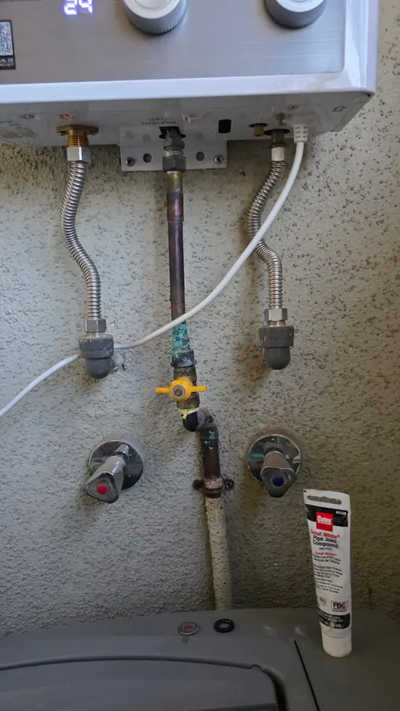 Conexiones de gas natural y agua bajo un calefont en la logia de un departamento