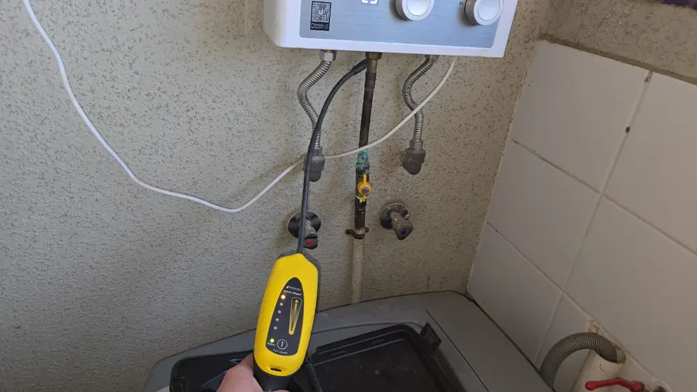 Detector de gas junto a las conexiones de un calefont