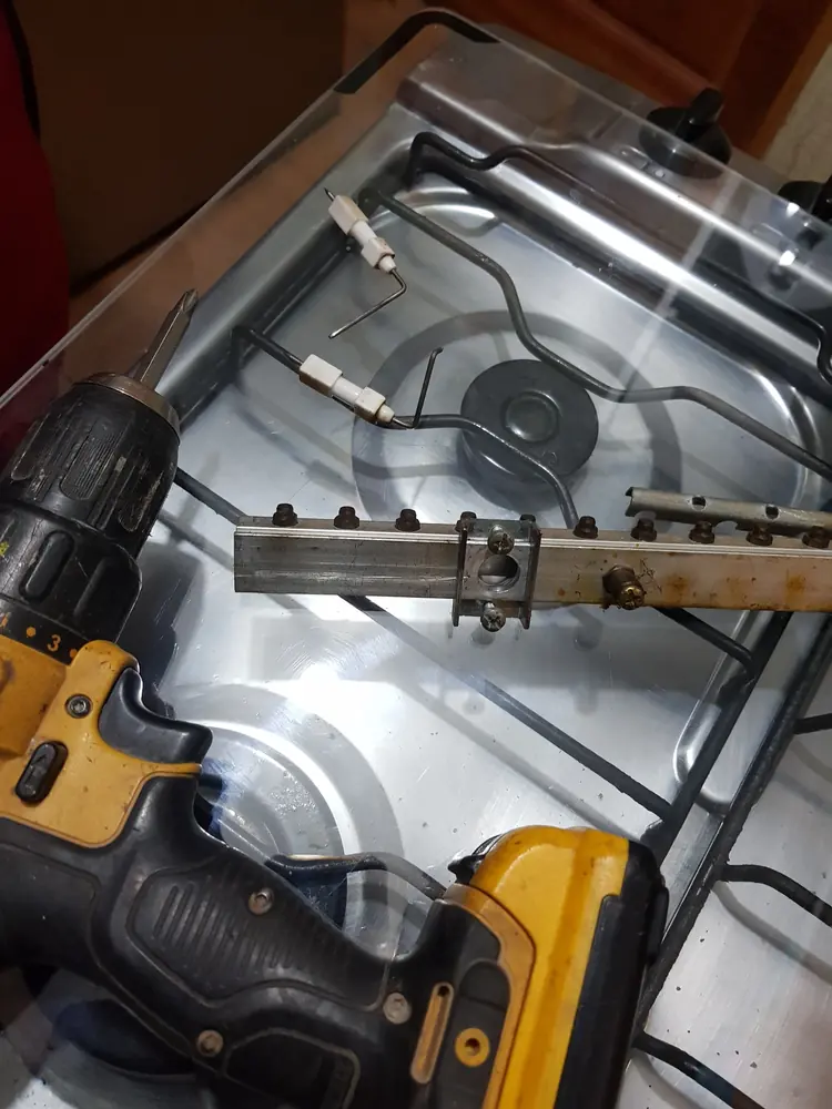 Encimera a gas abierta con su rampa de gas y un taladro durante la instalación