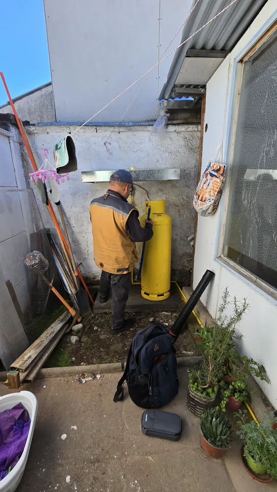 Técnico revisando la conexión de cilindros de gas de 45 kg en un patio