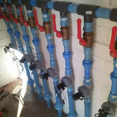 Colector de riego con electroválvulas y llaves de paso sobre un muro