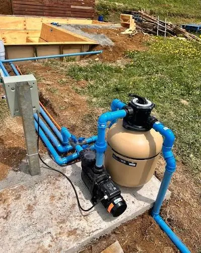 Filtro y bomba de piscina instalados en una parcela con cañerías hacia la piscina