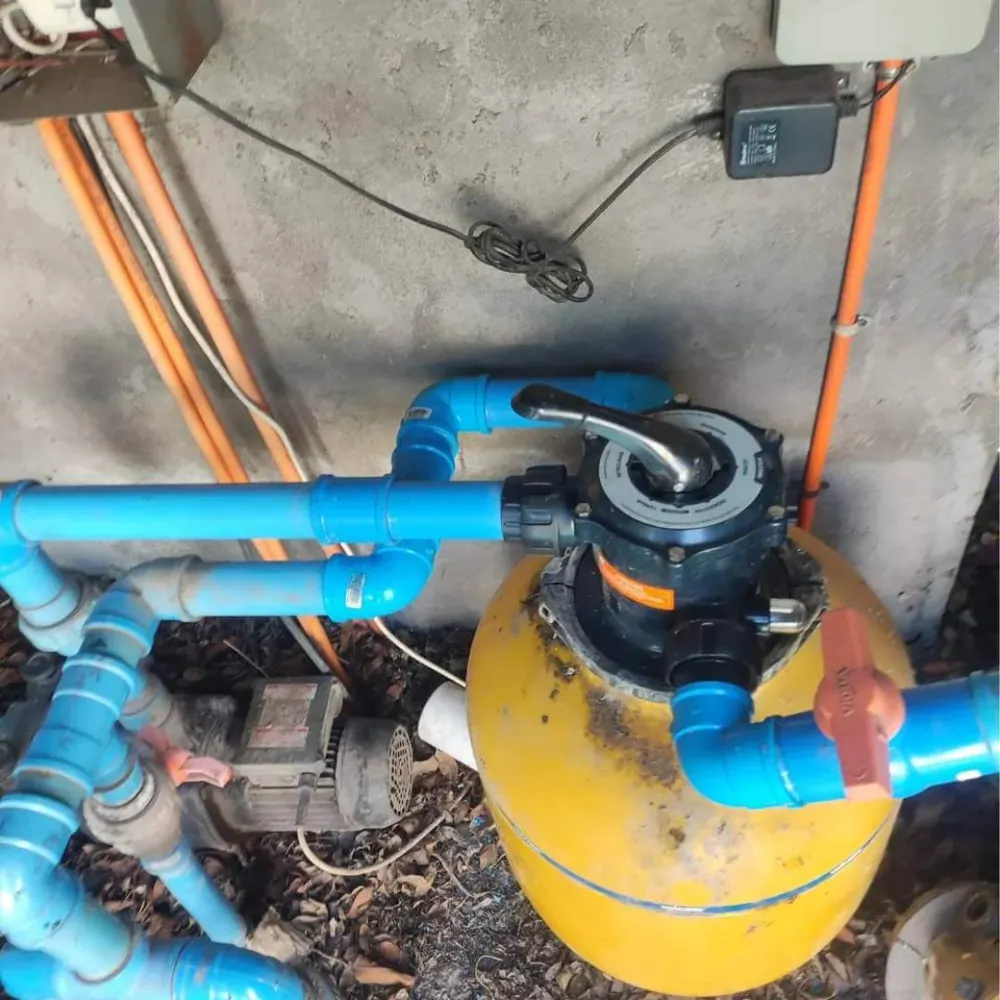 Filtro de arena amarillo con válvula selectora y cañerías azules
