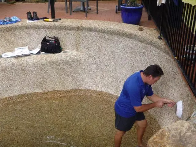 Técnico instalando un foco en el muro de una piscina vacía