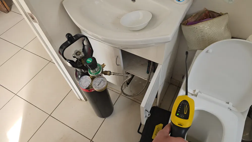 Detector de gas trazador junto a la base de un WC y una tina